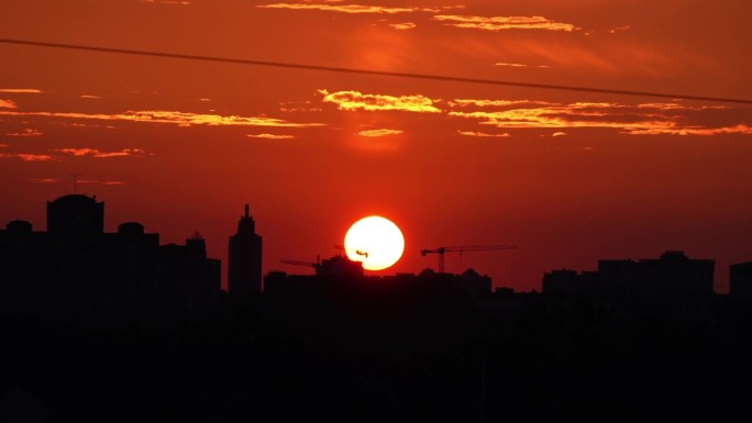 夕阳在大城市的背景下。夕阳与橘红色的天空在城市景观与建筑物的剪影