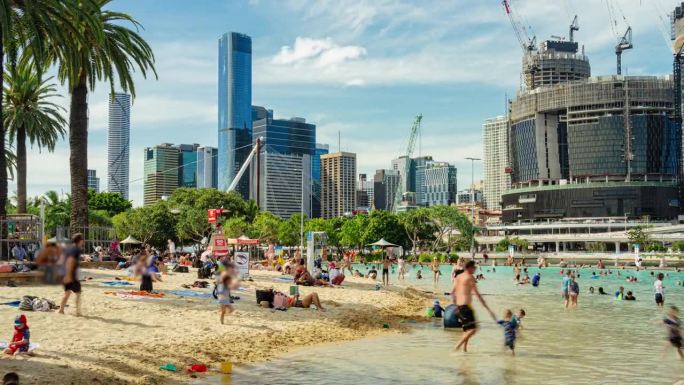 在澳大利亚昆士兰州布里斯班南岸的夏日周末，人们在阳光下的街道沙滩上放松和游泳