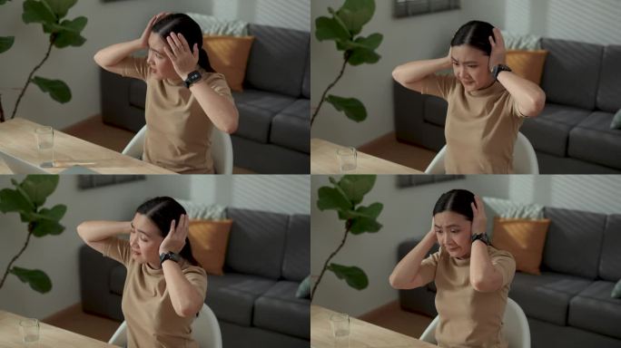 在家庭办公室使用笔记本电脑工作的亚洲女性感到无聊和厌烦，用手捂住耳朵。