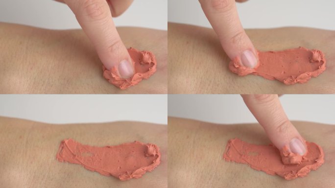 涂抹于手上的泥霜面膜。涂抹在手部皮肤上的橙色面霜面膜。斯沃琪粉桃面霜面膜。