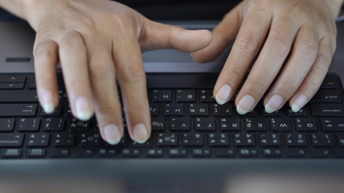 在笔记本电脑键盘上工作的女性的手