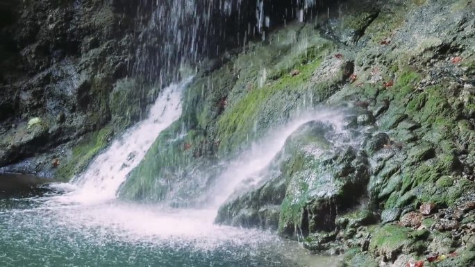瀑布喷涌在布满青苔的石头上，突出瀑布、青苔之美。宁静的瀑布，大自然中的青苔互动。瀑布的惊人视觉效果，