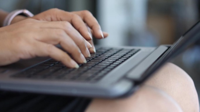 在笔记本电脑键盘上工作的女性的手