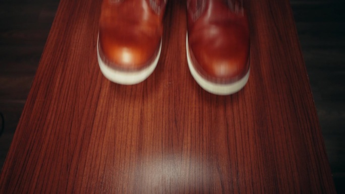 不认识的人把一双闪亮的棕色皮鞋放在桌子上