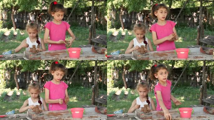 两个小女孩在院子里捏塑一个泥塑工艺品