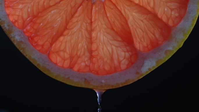 切片红葡萄柚汁滴在黑色背景，微距