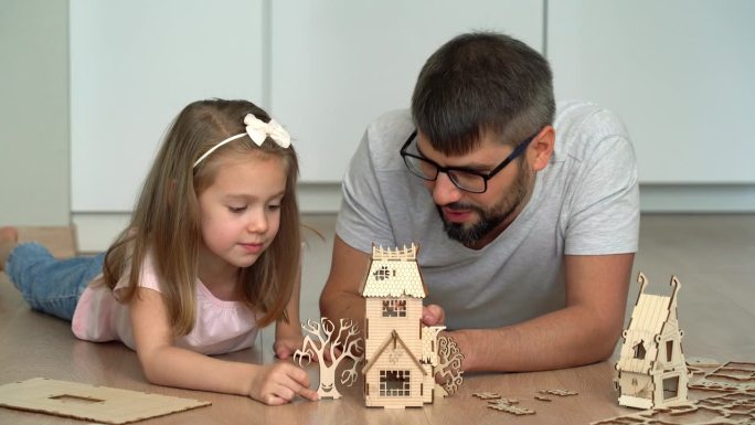 父女俩在家里搭建木结构布景特写