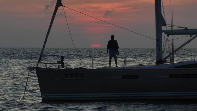 海上船上眺望落日的男人