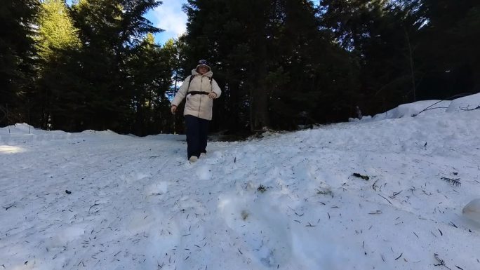 成年妇女在冬天走在雪山森林里。