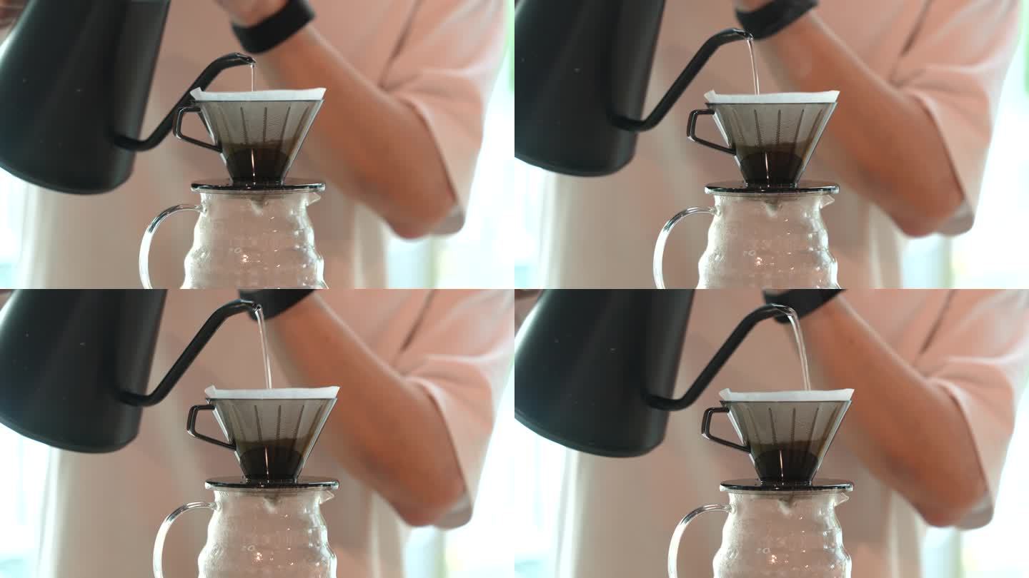在一个特写镜头中，咖啡师正在用滤纸将热水倒在磨碎的咖啡上，以制作滴漏咖啡