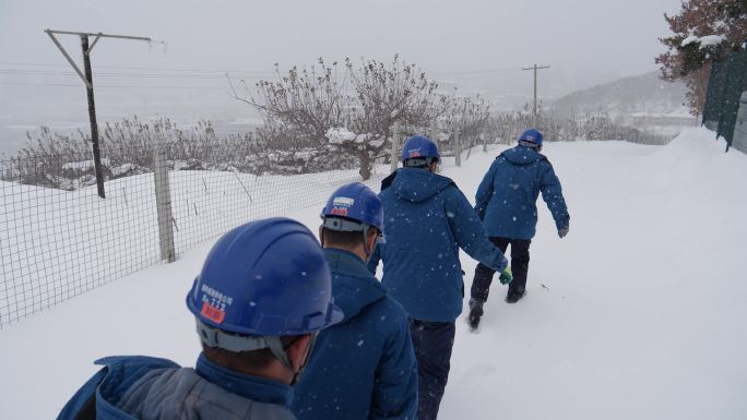 暴雪中电网工人登山巡线踩雪地