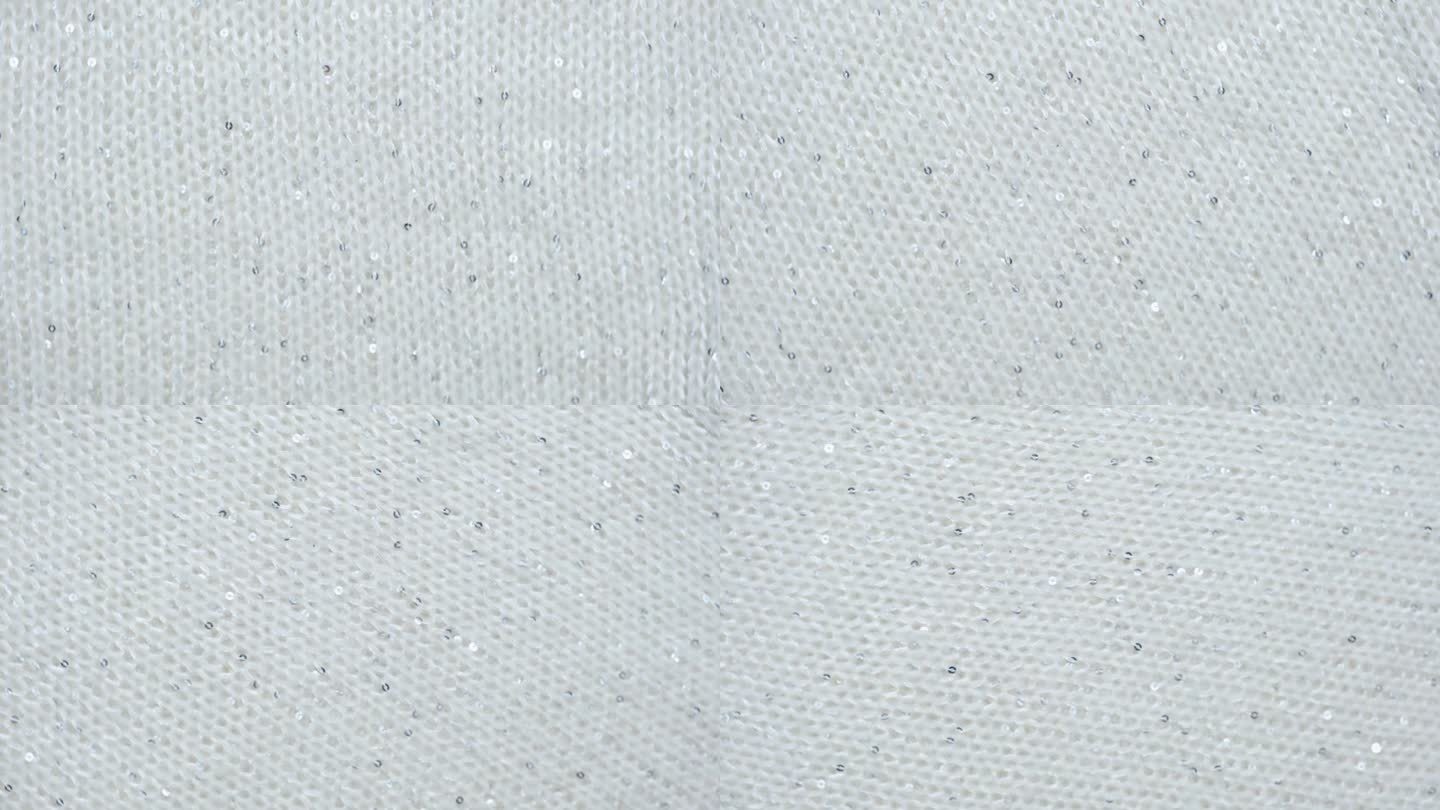 柔软的针织羊毛详细的纹理。天然织物近距离针织图案。白色针织品，温暖的羊绒表面。旋转,宏。舒适的纺织背