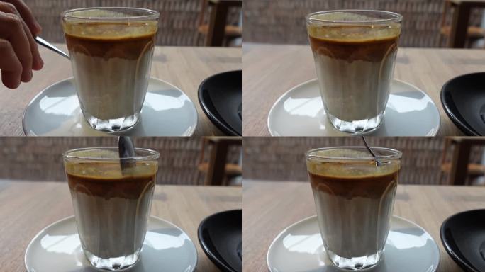 手和勺子搅拌混合脏咖啡，咖啡与牛奶在放松咖啡馆4k
