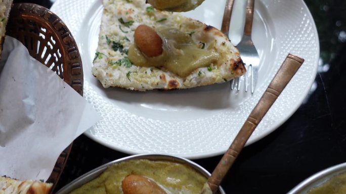 用勺子舀印度咖喱顶部的大蒜馕是一种亚洲印度食物