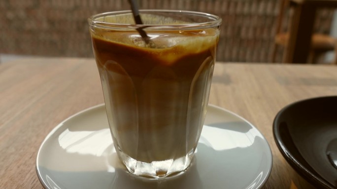 手和勺子搅拌混合脏咖啡，咖啡与牛奶在放松咖啡馆4k