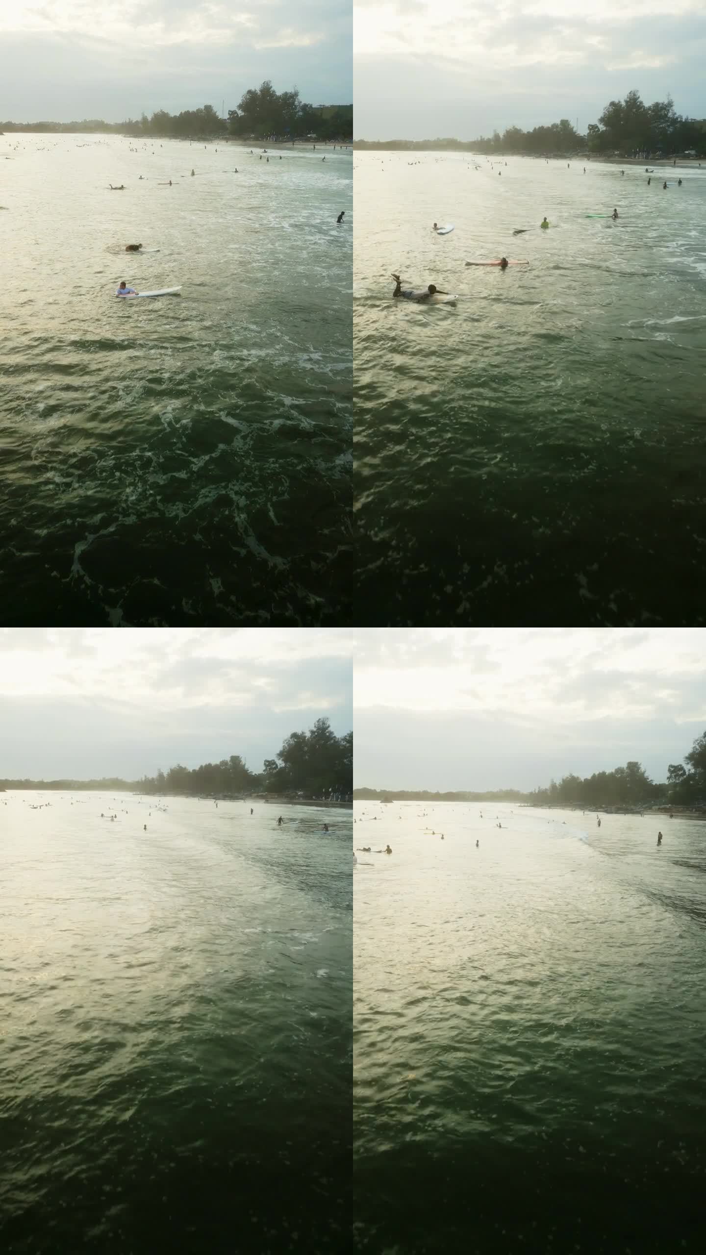 日落时海浪中的冲浪者鸟瞰图。密集的人群冲浪，在板上划桨，等待着海浪。充满活力的海景，在黄金时间从上面