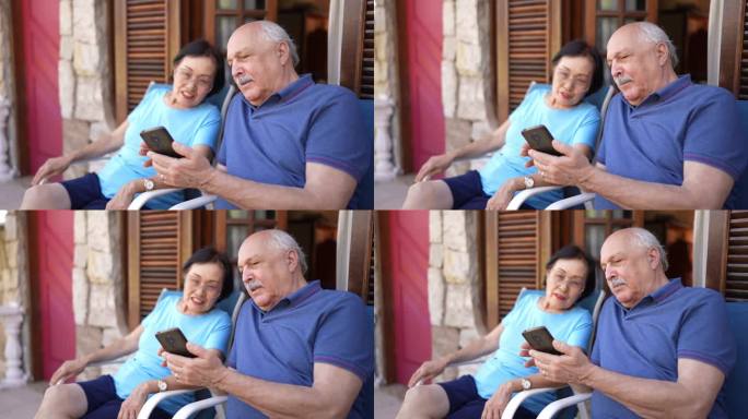 一位老人在酒店或房子的阳台上用手机给他的妻子看东西