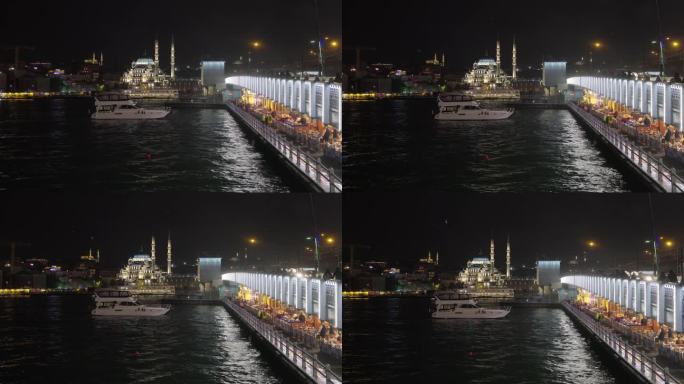手持拍摄的游艇在马尔马拉海加拉塔大桥与蓝色清真寺照明在夜间在伊斯坦布尔，土耳其