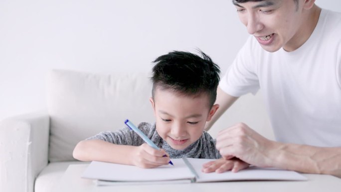 年轻的父亲检查家庭作业，帮助孩子在家学习