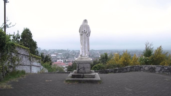 基座上的圣母玛利亚雕像俯瞰城市背景。手持