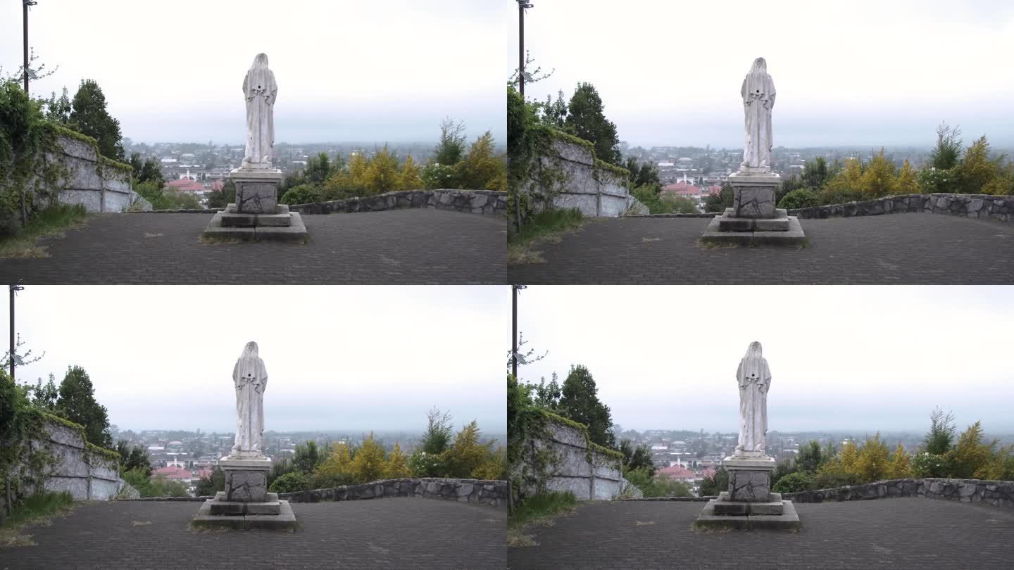 基座上的圣母玛利亚雕像俯瞰城市背景。手持