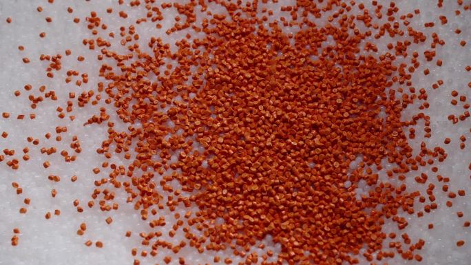 宏观框架的白色和橙色塑料颗粒。将聚合物复合材料倒入罐中，用于进一步生产和在特殊模具中铸造。生产