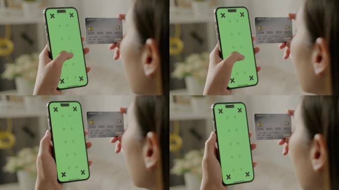 用智能手机购物的女人的手，绿色屏幕上有信用卡