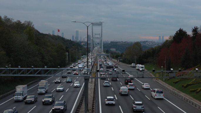 日落时分，土耳其伊斯坦布尔，博斯普鲁斯大桥上的车辆在树林中行驶