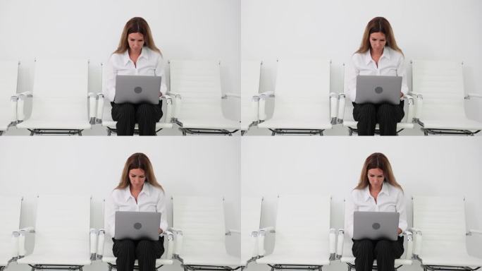 年轻的女经理坐在椅子上使用笔记本电脑