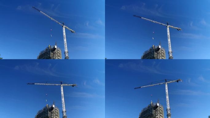 一台大型自爬式施工塔吊将设备吊到一栋正在施工的高层住宅楼上，云层吹过晴朗的蓝天