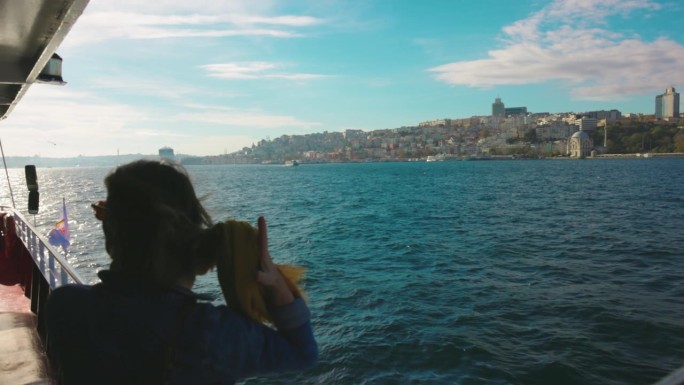 快乐的女游客在船上放松，享受博斯普鲁斯海峡的微风和美景