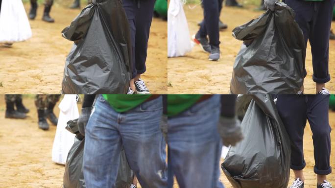 在公共场所收集垃圾的一名穿着运动鞋的女性志愿者的腿拿着黑色垃圾袋。