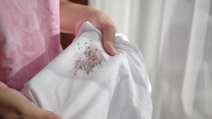 女人手拿衬衫，露出制作污渍