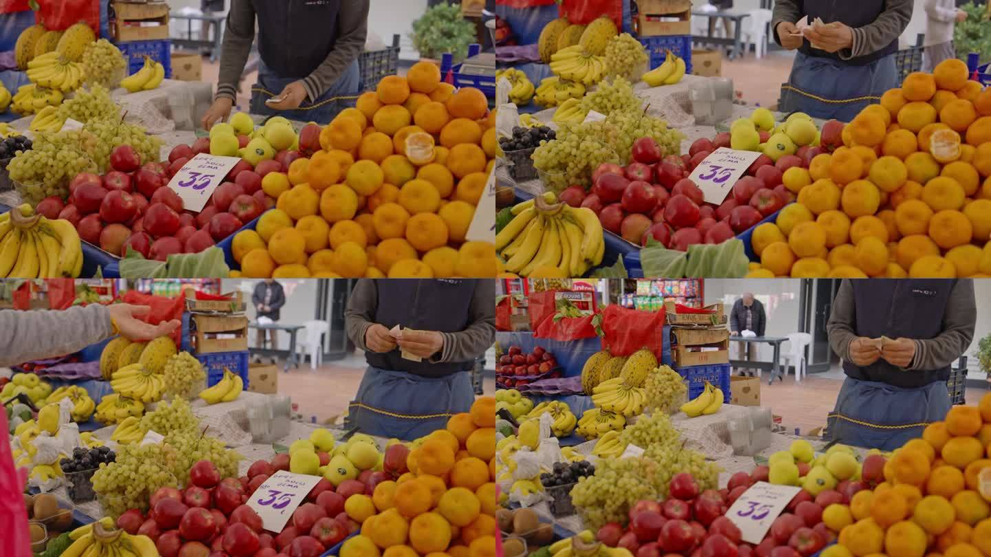 在土耳其伊斯坦布尔的集市摊位上，小贩手持镜头向妇女兜售水果