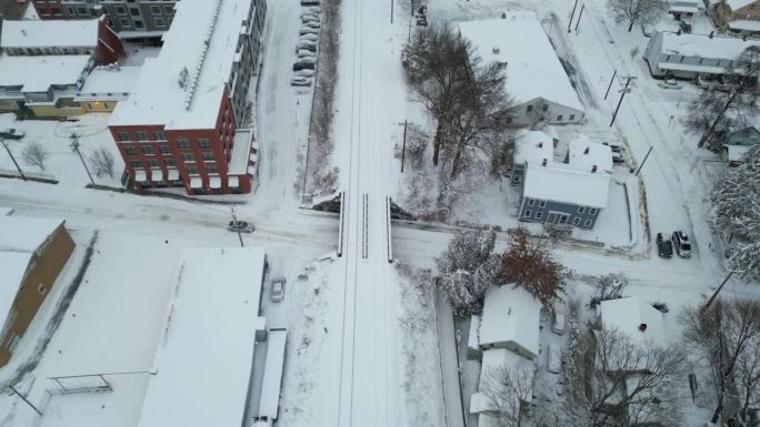 在结冰的道路上，汽车行驶在积雪覆盖的铁轨下，鸟瞰向下倾斜