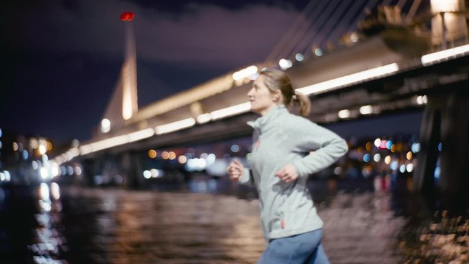 夜色中，女子沿着博斯普鲁斯海峡与模糊的金角地铁大桥慢跑。女人跑。蓝色的小时。