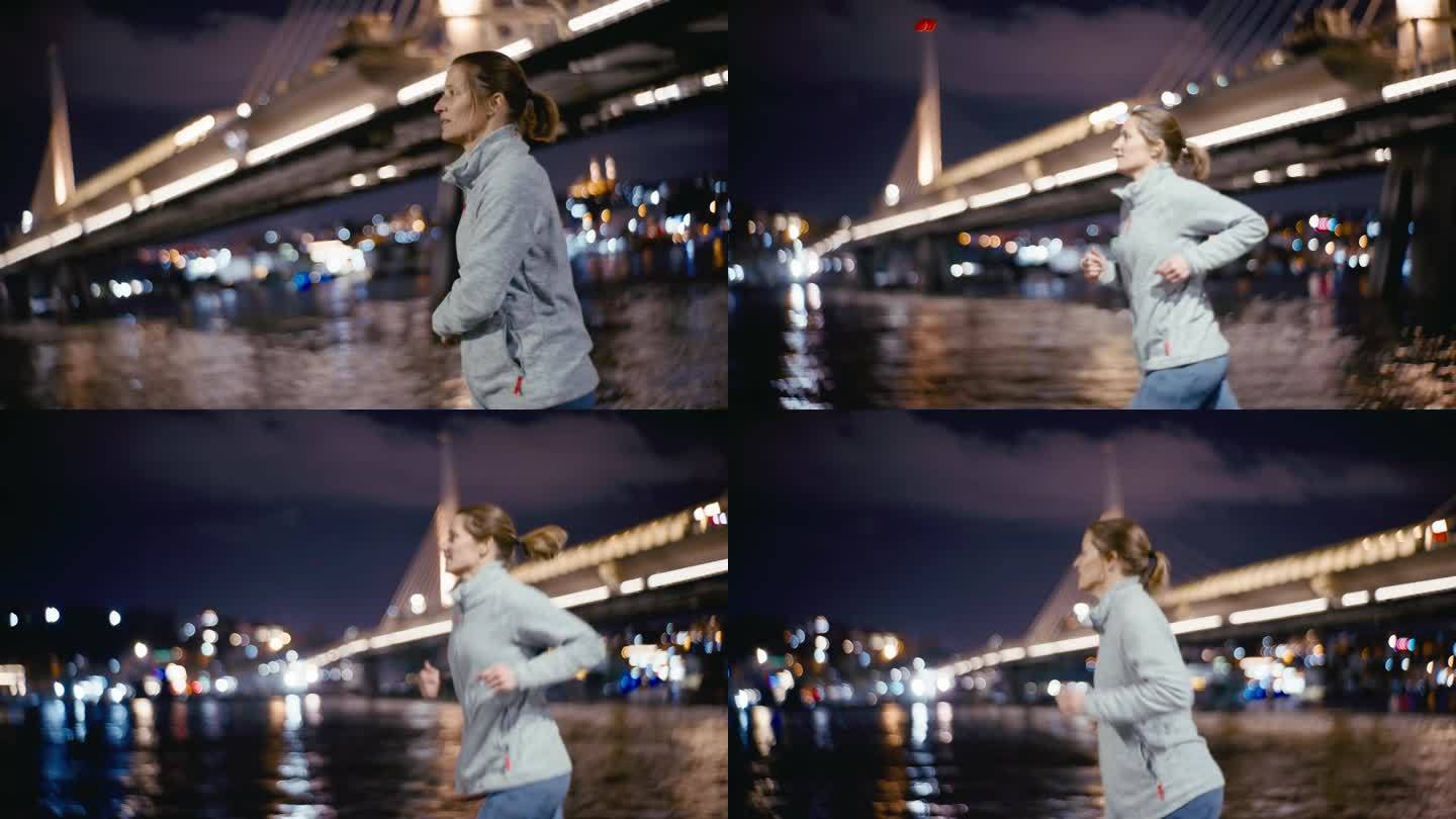 夜色中，女子沿着博斯普鲁斯海峡与模糊的金角地铁大桥慢跑。女人跑。蓝色的小时。
