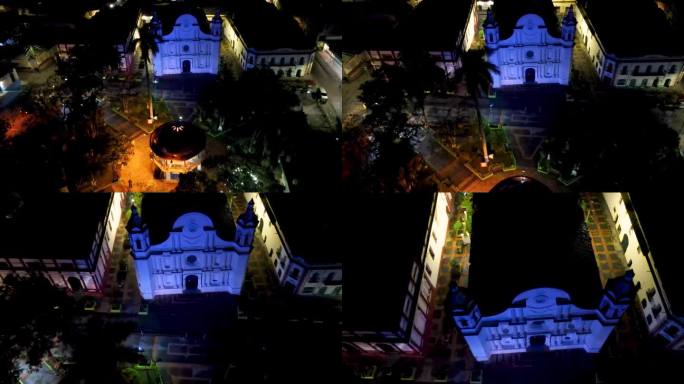 在洪都拉斯圣罗莎德科潘的一座古色古香的大教堂上空拍摄的电影航拍摄影车，它被蓝色的灯光照亮