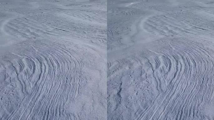 冬天的雪堆在空旷的土地上被风塑造出抽象的雪的纹理