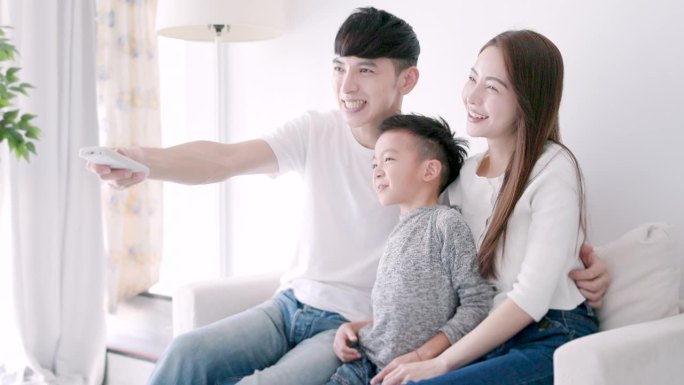 放松的亚洲家庭在家里一起看电视