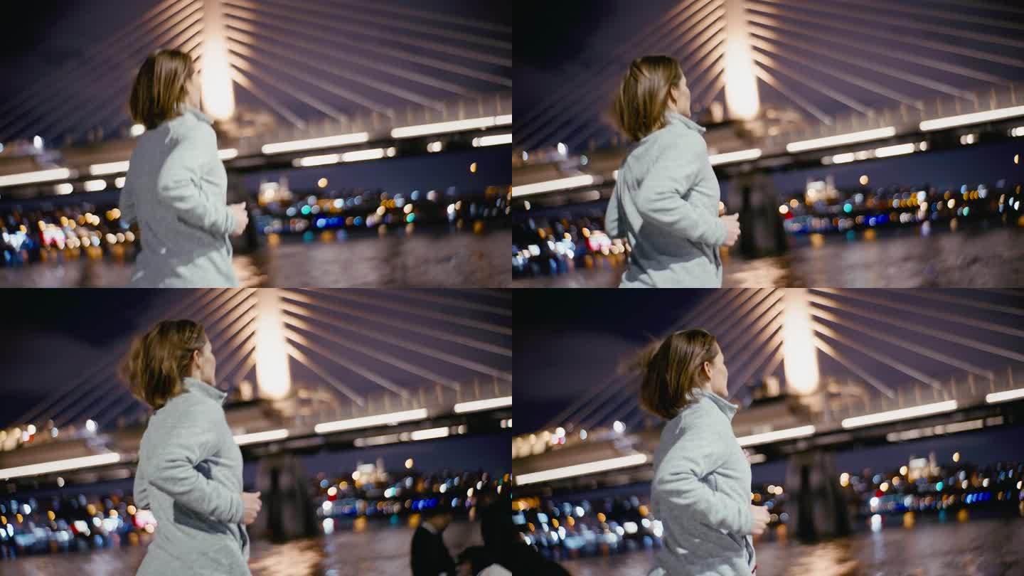 夜晚，一名女子向灯火通明的金角地铁大桥慢跑