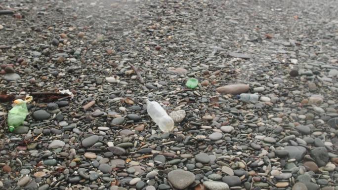 海滩上的塑料瓶等垃圾在雾、湿、雪、雨天气。塑料污染、垃圾和生态问题的危机观念。