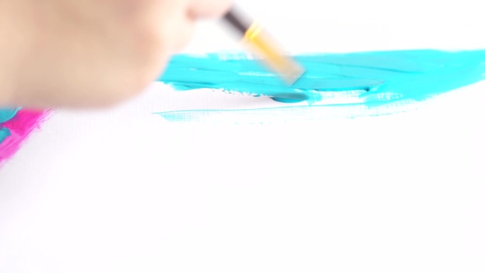 孩子手握画笔画油画的特写。在画布上画蓝色和粉红色的线条。
