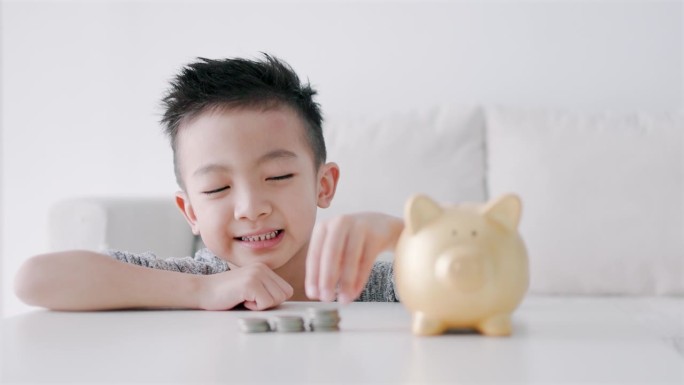 快乐的亚洲男孩把硬币放进存钱罐