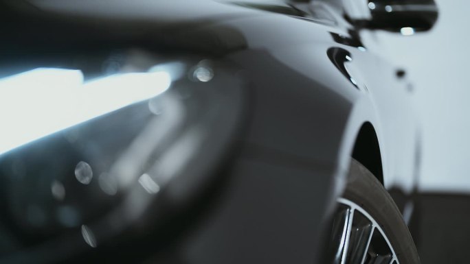 极近距离的相机pan闪亮的反光黑色金属表面的一个全新的蜡车侧面和车轮