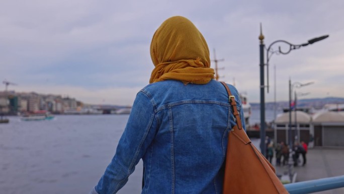 女游客在海滨长廊上欣赏博斯普鲁斯海峡美景的后景。享受伊斯坦布尔的女人。