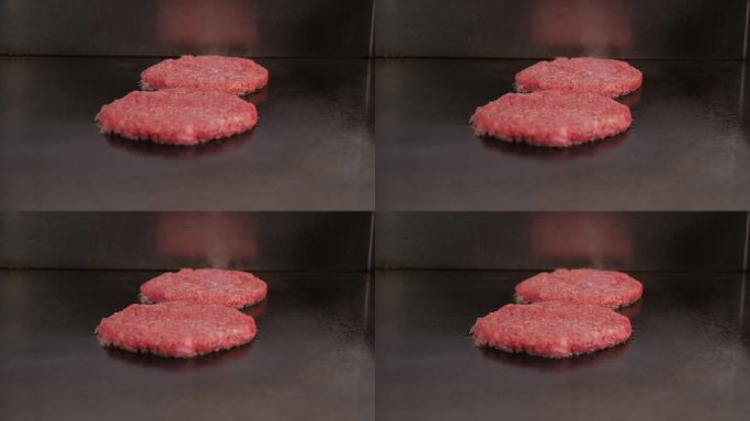 餐厅厨房里煎的两个肉汉堡的特写。