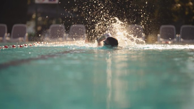 SLO - MO熟练男子游泳运动员在阳光下示范自由泳技术