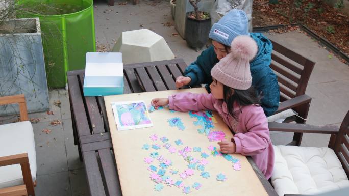 妈妈与女儿在院子木桌子上玩拼图