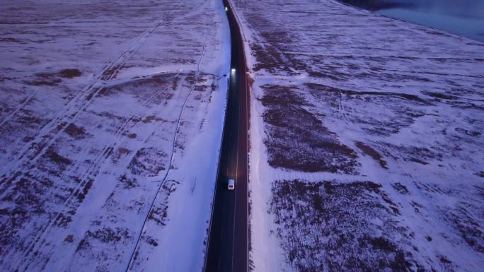 傍晚行驶在雪地公路的汽车